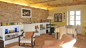 A cozy living room with a brick wall, a dining area with a table and chairs, and a shelf with various items. - Il Marchese del Grillo by Interhome (Capriglio)