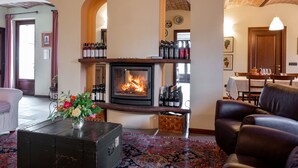 Un salon chaleureux avec une cheminée, un canapé en cuir et une table basse agrémentée d’un vase de fleurs.