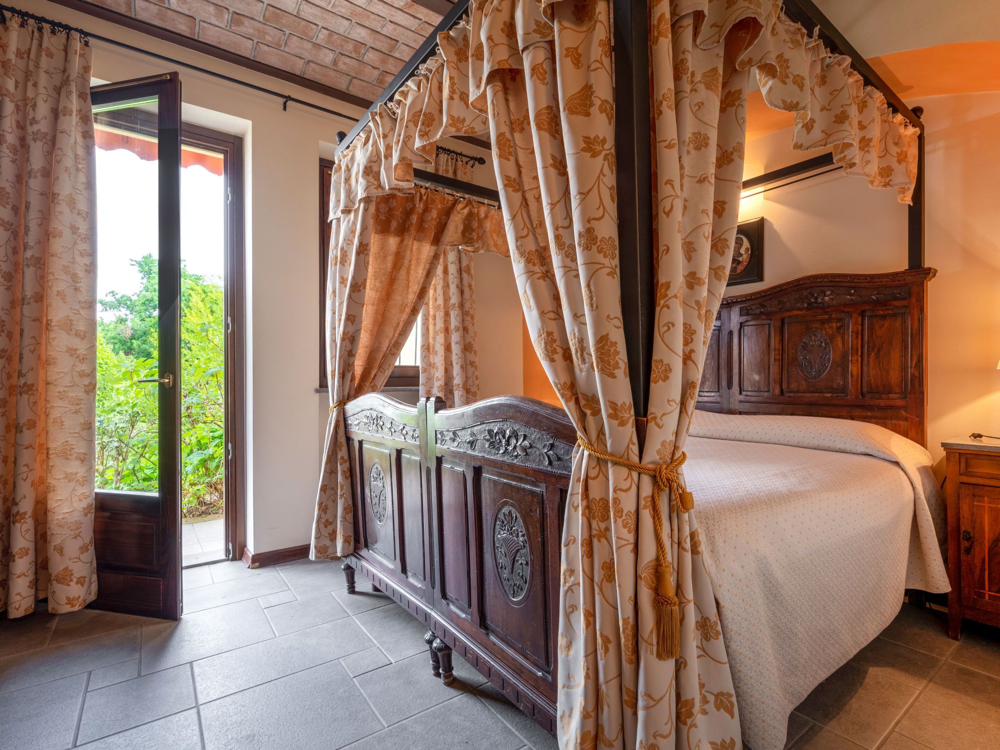 Ein Schlafzimmer mit einem Himmelbett, einem Holzkopfende und Blick auf Grün.