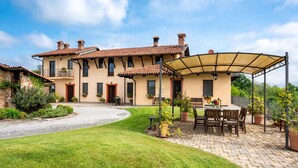 Une grande maison dotée d’un patio, d’un espace salon abrité et d’une pelouse bien entretenue.