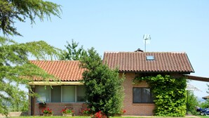 Une maison à deux étages, avec un toit recouvert de tuiles, une façade en briques et une petite antenne parabolique.