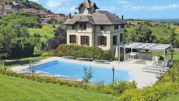 Une maison à deux étages avec une piscine, entourée d’une végétation luxuriante et offrant une vue sur une ville lointaine.
