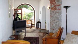 A cozy living room with a television, leather sofas, and a brick wall. - Cascinotta by Interhome (Bastia Mondovì)