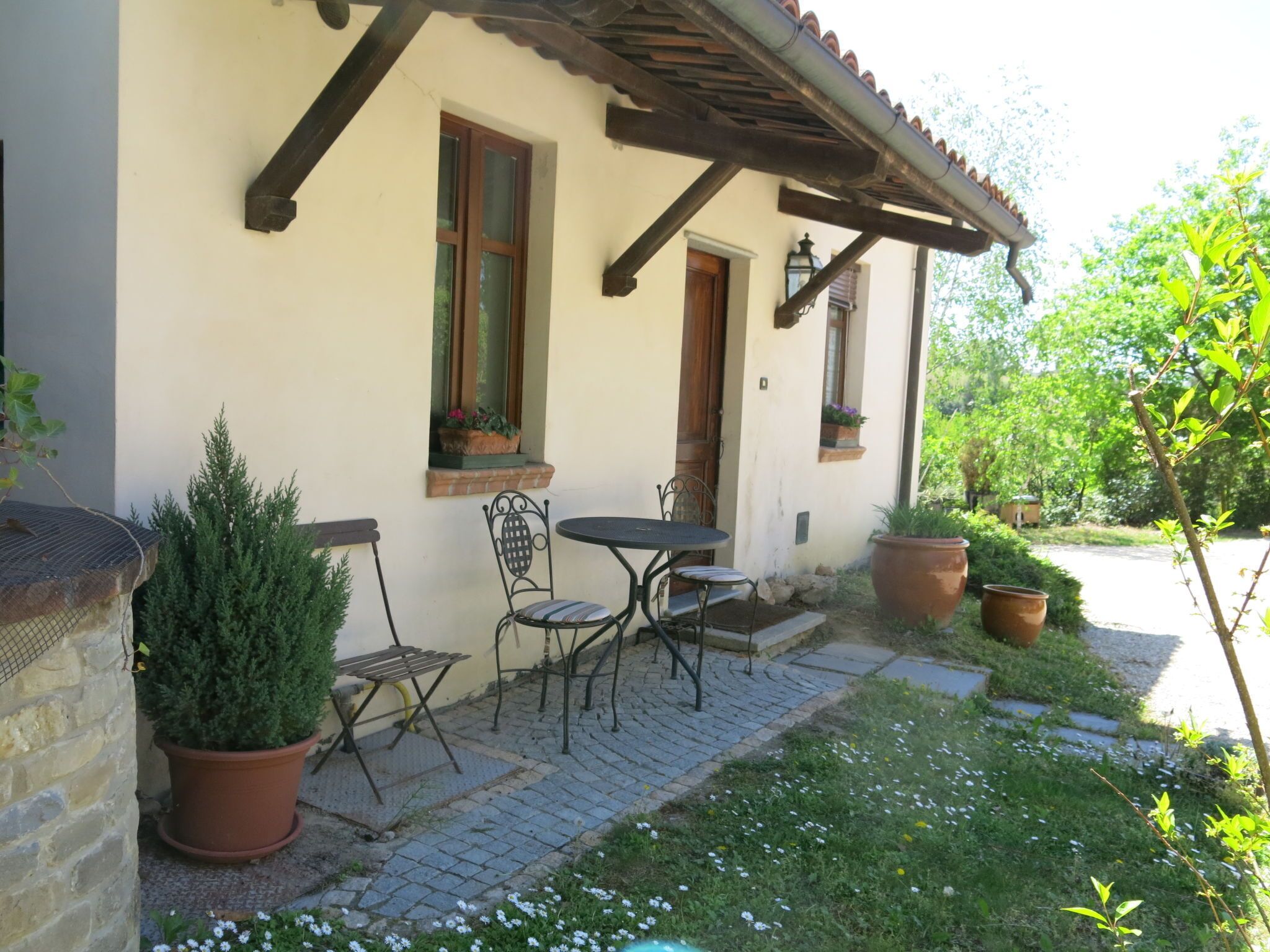 A house with a patio area featuring a table and chairs, potted plants, and a small garden.