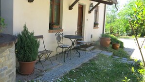 A house with a patio area featuring a table and chairs, potted plants, and a small garden. - I Grilli by Interhome (Castagnole Lanze)
