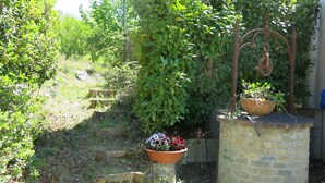 A garden with a stone wall, wooden steps, and potted plants. - I Grilli by Interhome (Castagnole Lanze)