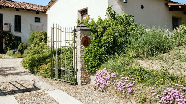 A two-story building with a tiled roof, a stone wall, and a metal gate. - I Grilli by Interhome (Castagnole Lanze)