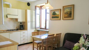 A compact kitchen with a dining area, a sofa, and a window with curtains. - I Grilli by Interhome (Castagnole Lanze)
