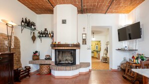 Ein gemütliches Wohnzimmer mit Kamin, Fernseher an der Wand und Ziegeldecke.