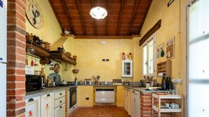 Eine Küche mit Terrazzoboden, Holzschränken, einer Mikrowelle und einem Kühlschrank.