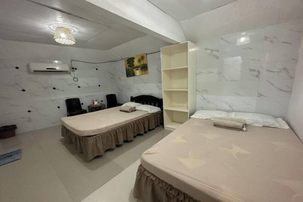 Ein Zimmer mit zwei Betten, einem Schreibtisch, einem Stuhl, einem Bücherregal und einer Klimaanlage.
