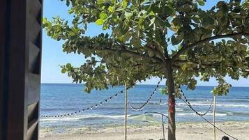 A beach scene with a tree, a chair, and the ocean.
