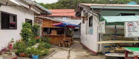 A narrow alley with a small outdoor seating area, a wooden table, and a signboard.