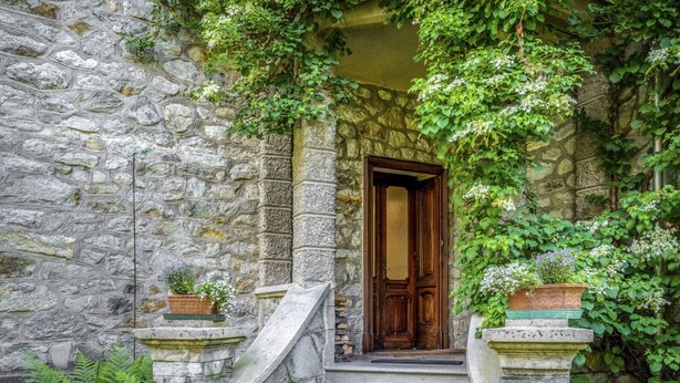 A stone building with a wooden door, stone steps, and potted plants. - Villa Biino by Interhome (Ala di Stura)