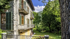 A stone building with balconies, a fenced garden, and a mountainous backdrop. - Villa Biino by Interhome (Ala di Stura)