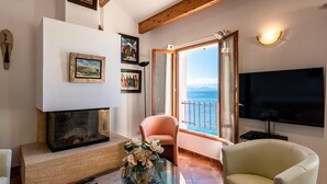 A living room with a fireplace, a television, and a view of the sea. - Maison Balbi by Interhome (Canari)