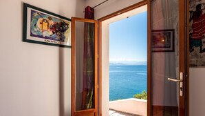 A room with a view of the sea, a framed Kandinsky painting, and a wooden door. - Maison Balbi by Interhome (Canari)