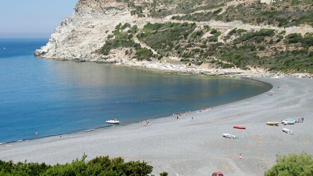 A coastal beach with rocky cliffs, clear blue sea, and several boats. - Maison Balbi by Interhome (Canari)