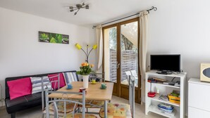 A modern living room with a sofa, dining table, chairs, a TV, and a bookshelf. - La Petite Toscane by Interhome (Cabris)