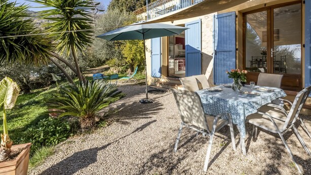 A patio with a table and chairs, surrounded by greenery and a gravel path. - La Petite Toscane by Interhome (Cabris)