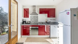 A modern kitchen with red cabinets, a stainless steel range, and a white refrigerator. - La Petite Toscane by Interhome (Cabris)