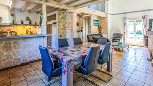 A spacious kitchen with a stone wall, a dining area with a table set for six, and a bar area with a counter. - Labenne Océan by Interhome (Labenne)