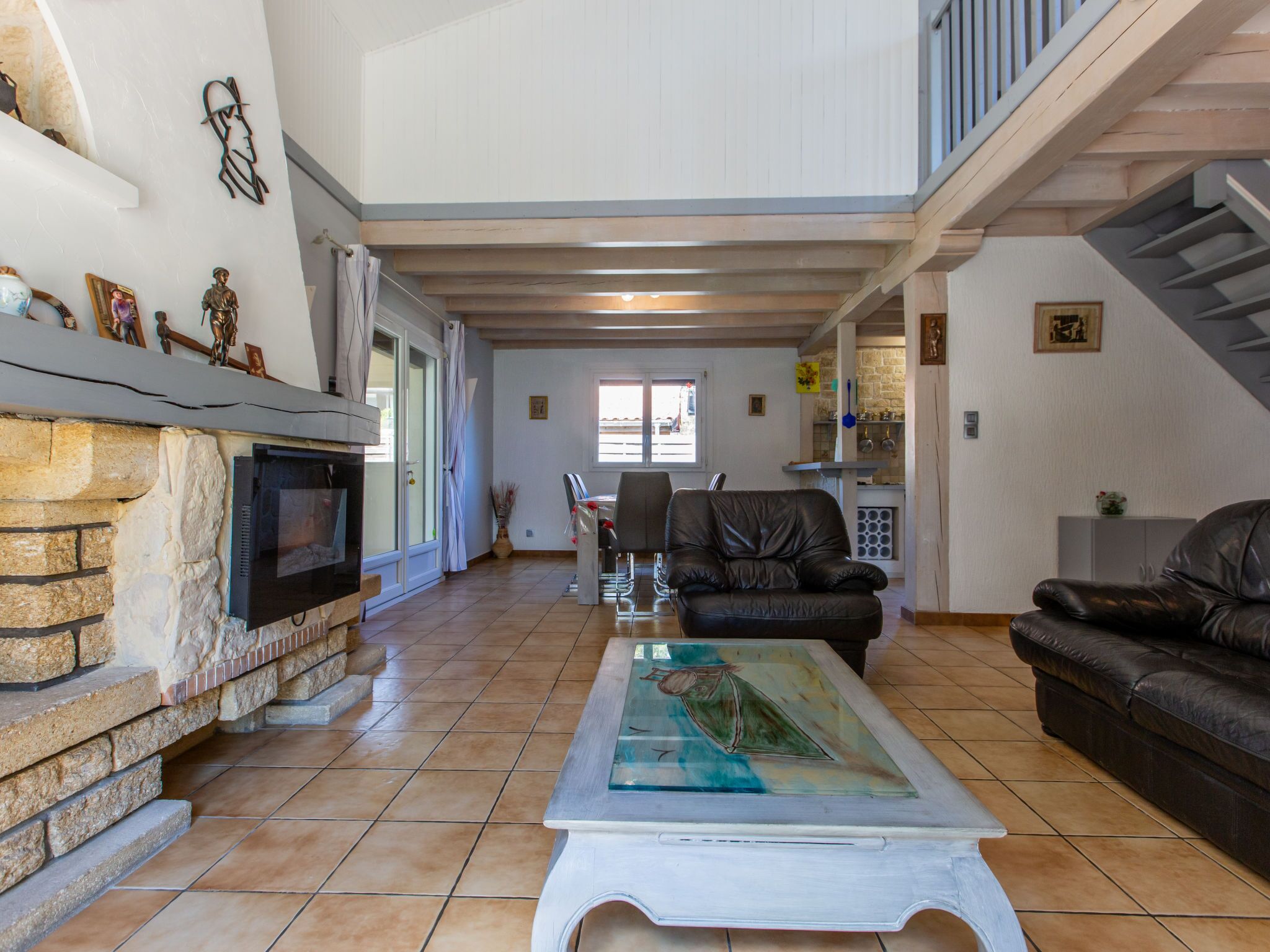Amplia sala de estar con chimenea de piedra, sofás de cuero y una mesa de centro de vidrio.