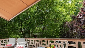 Eine Terrassengruppe im Freien mit einem runden Esstisch, umgeben von Stühlen und einem dekorativen Zaun.