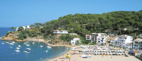 A beach with boats, people, and buildings.
