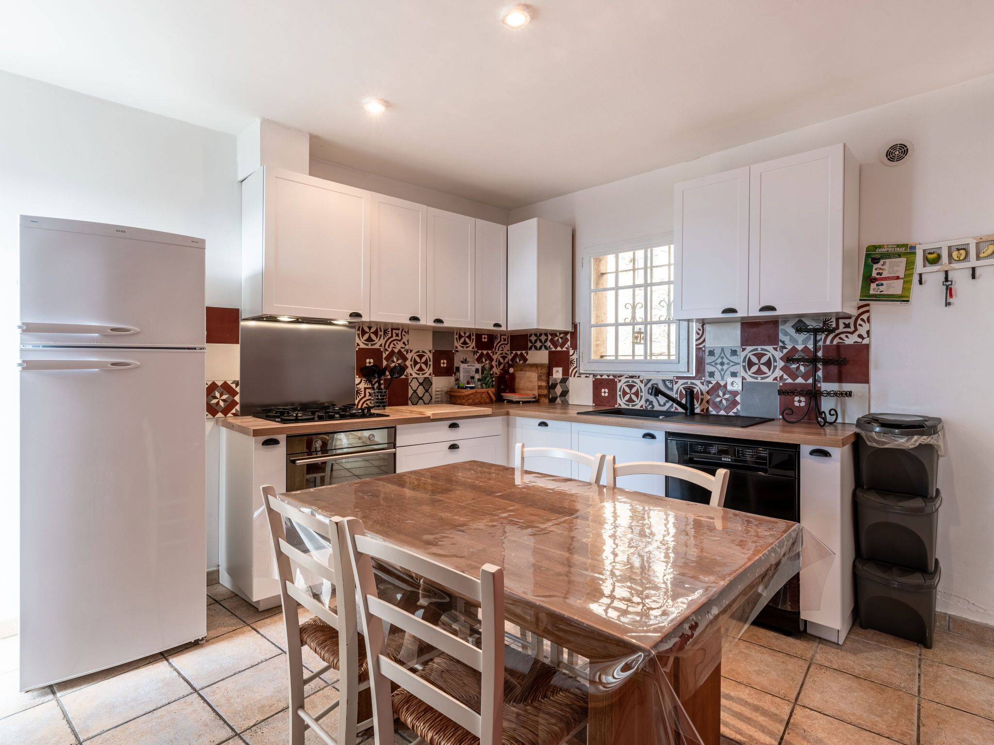 A compact kitchen with white cabinets, a wooden countertop, and a tiled backsplash.