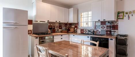 A compact kitchen with white cabinets, a wooden countertop, and a tiled backsplash.