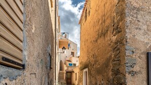 Un carreró estret de pedra entre edificis, amb parets de pedra i persianes de fusta.