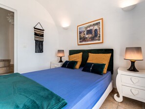 Une chambre à coucher comprenant un lit, deux tables de chevet, une œuvre d’art accrochée au mur et un élément décoratif mural.