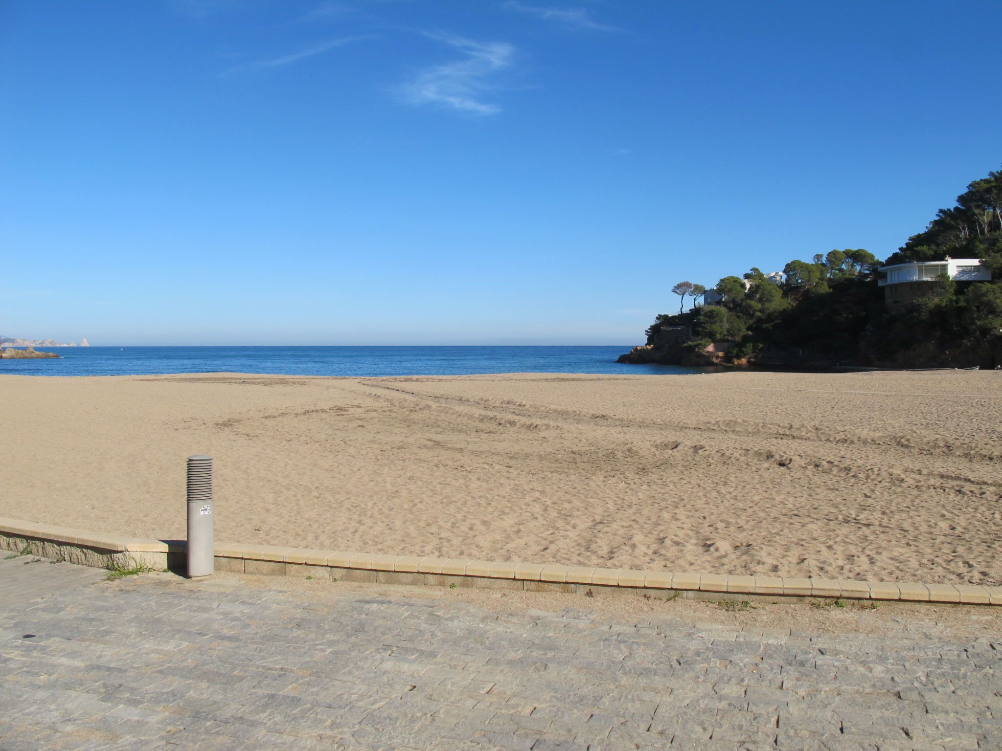 Ein weiter Sandstrand unter blauem, wolkenlosem Himmel.