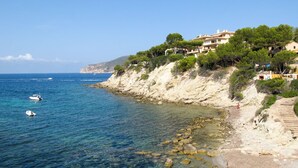 Uma área costeira com águas azuis cristalinas, costa rochosa e edifícios construídos em um penhasco.