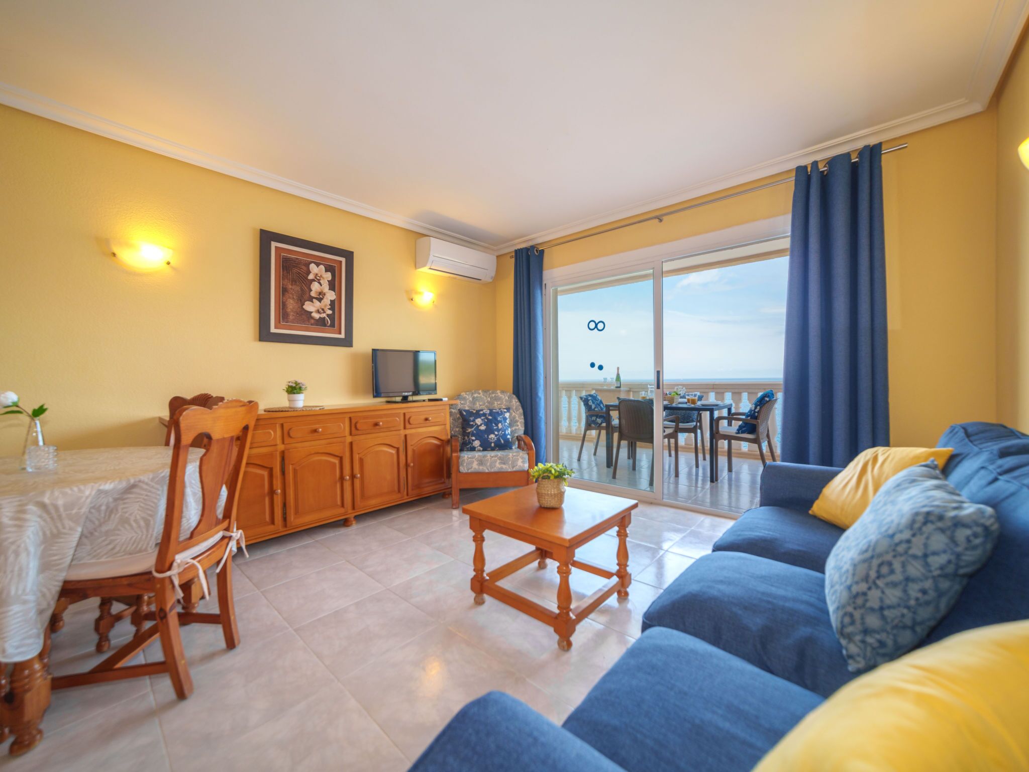 Una sala de estar con sofá, muebles de madera, una mesa de comedor y un balcón con vistas.