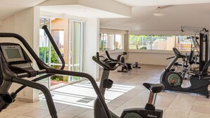 A gym with multiple exercise machines, including treadmills and elliptical trainers, with large windows providing natural light and views of the outdoors. - MB2 sans vue mer by Interhome (Moriani-Plage)