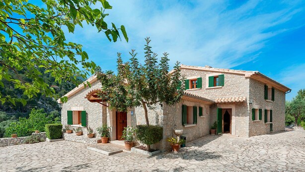 A stone house with a tiled roof, green shutters, and a stone courtyard. - Es Barracar by Interhome (Caimari)