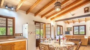 Une cuisine spacieuse avec des meubles en bois, un coin repas avec une table pour quatre personnes et un salon confortable avec un canapé et une télévision.