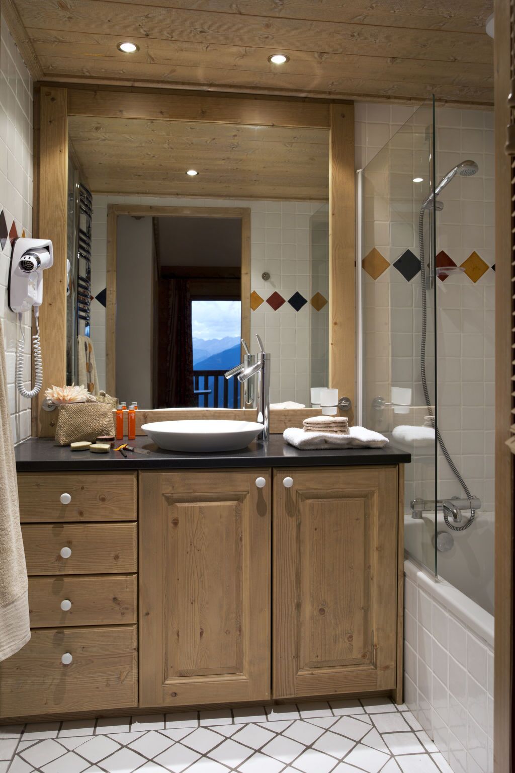 A bathroom with a wooden vanity, a large mirror, a sink, and a shower.
