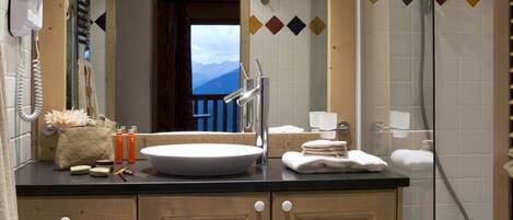 A bathroom with a wooden vanity, a large mirror, a sink, and a shower.