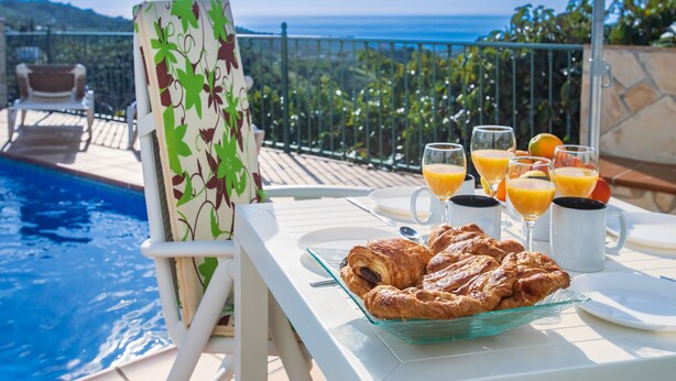 A poolside breakfast setup with croissants, orange juice, and coffee.