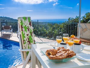 Desayuno junto a la piscina con cruasanes, zumo de naranja y café.