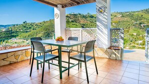 A terrace with a table and chairs, a decorative plate, and a view of a hilly landscape.