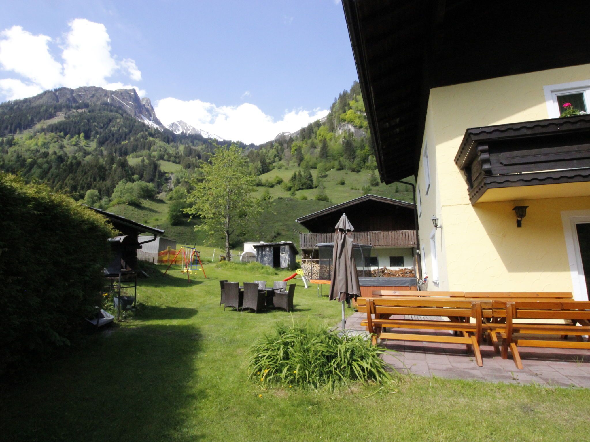 A rural mountain setting with a yellow building, outdoor seating, and a playground.