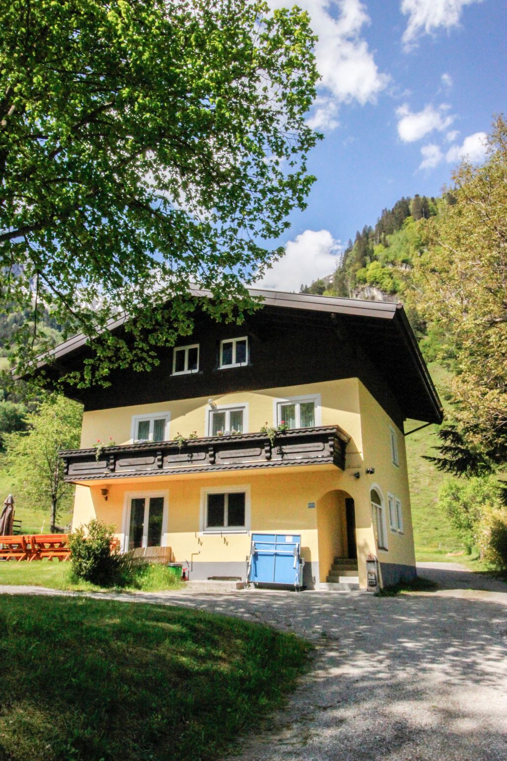 A two-story chalet with a balcony, a front door, and a small porch area.