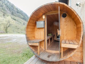 Una sauna de madera con bancos y un asiento de banco, un banco con toallas y un panel de control.