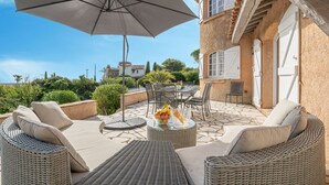 An outdoor patio with wicker furniture, a table with fruits, and a large umbrella.