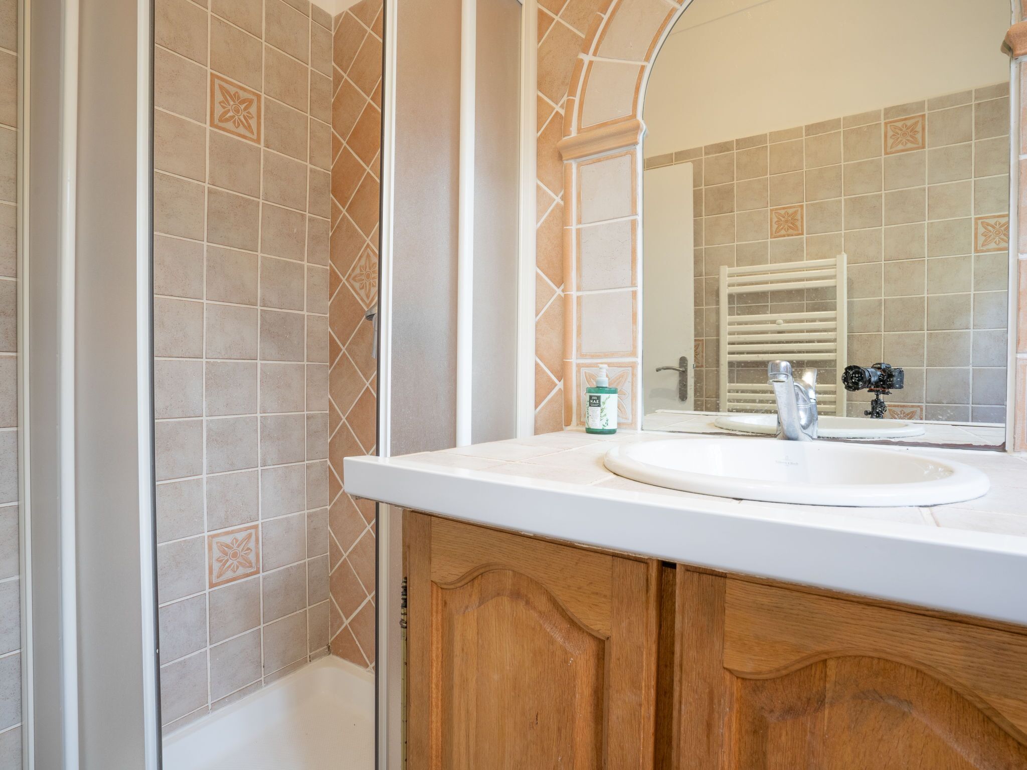Ein Badezimmer mit einem weißen Waschbecken, Holzschränken und beige-karierten Fliesen.