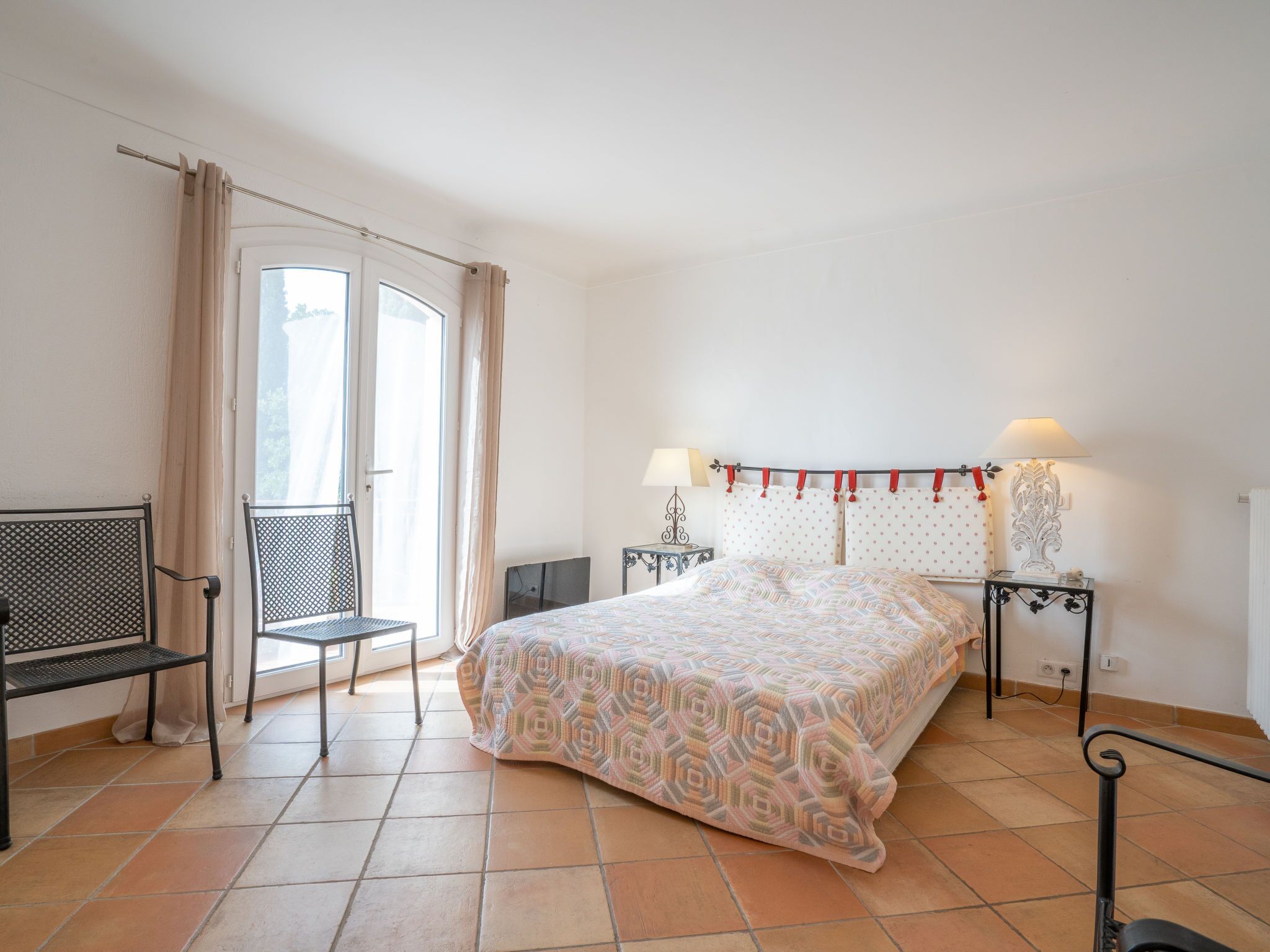 Une chambre à coucher avec un lit, une chaise, une table et une fenêtre avec des rideaux.